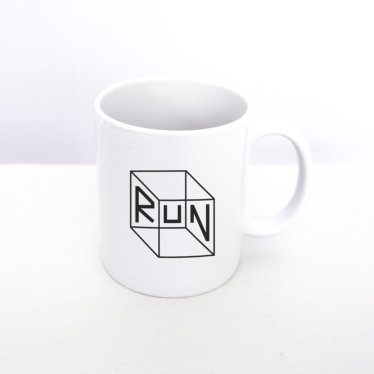 Our signature RUN cube design on a white dishwasher safe mug that is part of our RUN gift box set from TWO CORRALS Lifestyle Running Brand